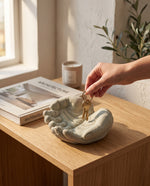 Cargar imagen en el visor de la Galería, Mano dejando llaves en la escultura decorativa manos chicas color cemento sobre mesa.