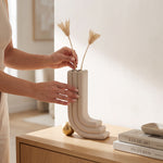 Cargar imagen en el visor de la Galería, Manos colocando flores en el jarrón decorativo Oguz beige moderno sobre una mesa de recibidor.
