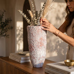 Cargar imagen en el visor de la Galería, Mujer decorando con flores secas el jarrón Hiro chico de cerámica texturizada sobre un mueble de madera.