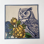 Cargar imagen en el visor de la Galería, Mantel individual cuadrado sintético con ilustración de búho y flores amarillas sobre fondo claro con borde azul.