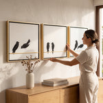 Cargar imagen en el visor de la Galería, Mujer colocando el set de 3 cuadros Nido para pared de 0.80x0.80 cm en un salón cálido y moderno.