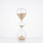 Cargar imagen en el visor de la Galería, Reloj de arena Opus de vidrio decorativo vertical con tres bulbos y arena clara sobre base blanca.