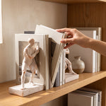 Cargar imagen en el visor de la Galería, Mano sacando un tomo del set de sujetalibros decorativos hombre de resina para libros en estante.