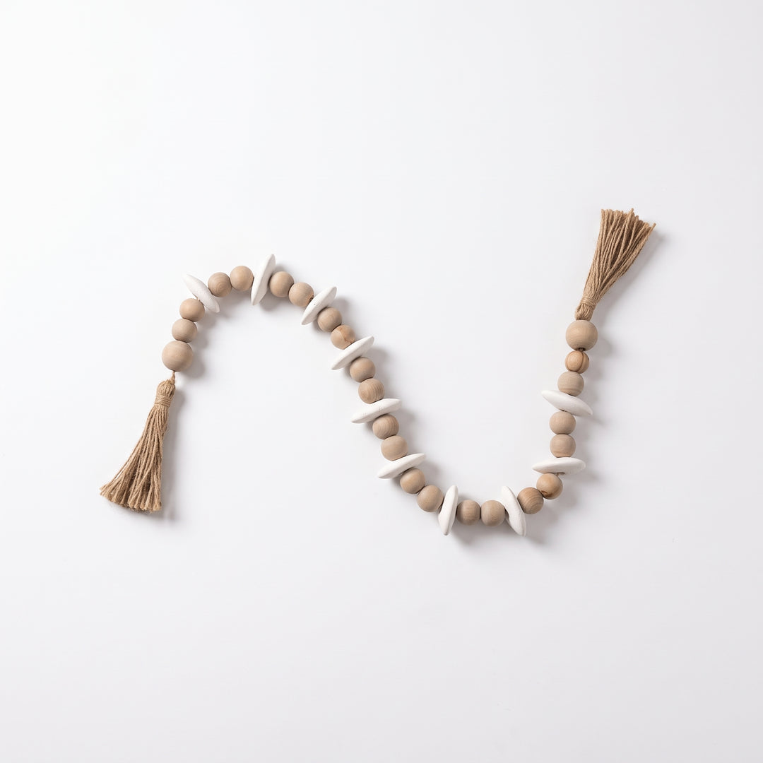 Cuentas decorativas Mala Sina de madera con borlas para mesa y repisa sobre fondo blanco.