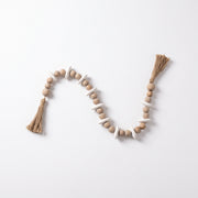 Cuentas decorativas Mala Sina de madera con borlas para mesa y repisa sobre fondo blanco.