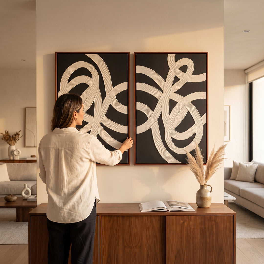 Mujer acomodando el cuadro abstracto Conexión en acrílico con relieve y moldura caoba sobre un aparador.