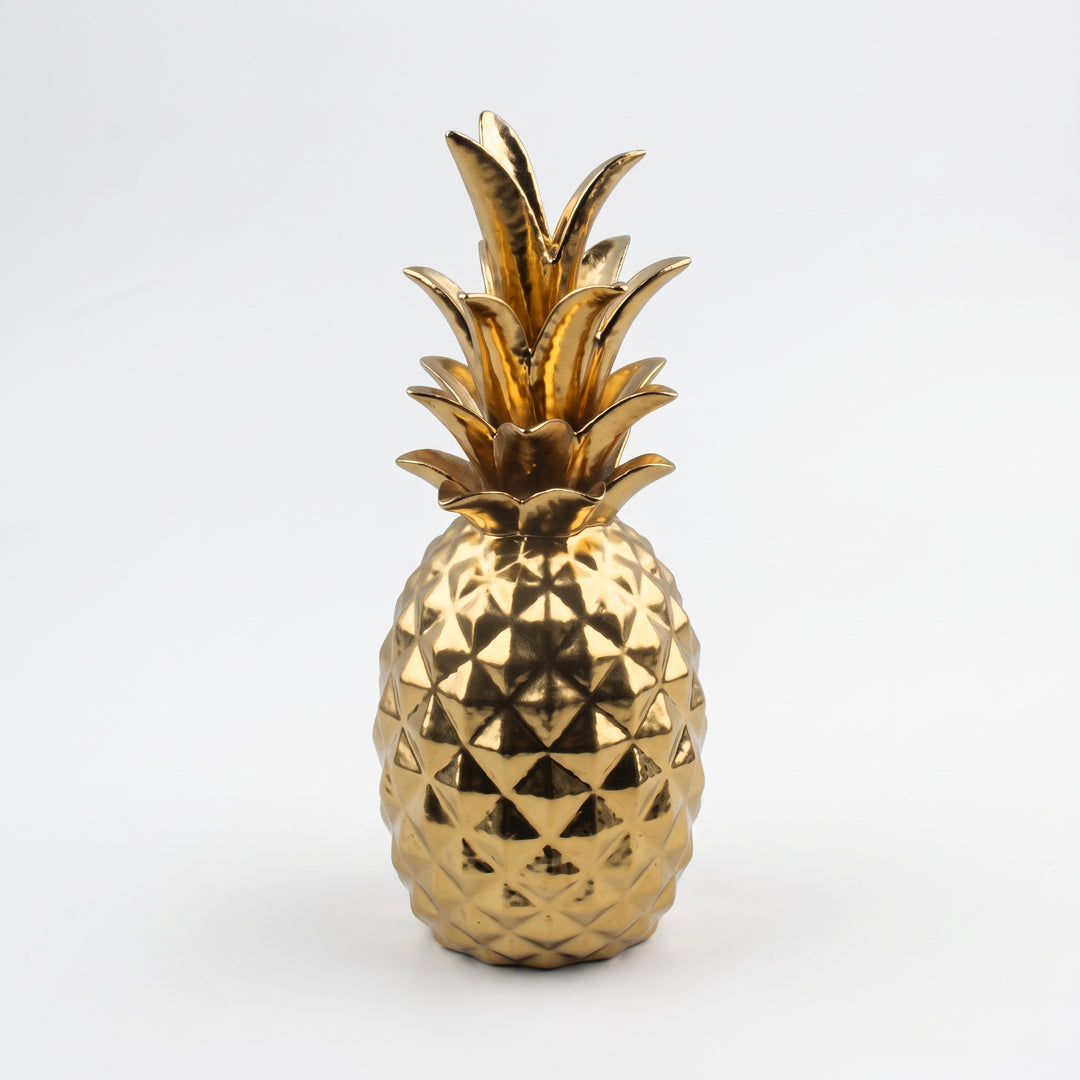 Figura decorativa Piña Hollywood de cerámica dorada brillante sobre fondo blanco.