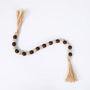 Tira de cuentas decorativas Mala Jinpa de MDF en negro y madera natural con borlas de rafia.