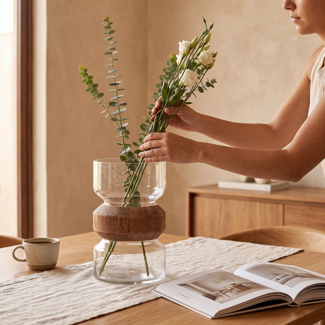Mujer colocando flores en el jarrón Adam grande de cristal sobre una mesa de comedor.