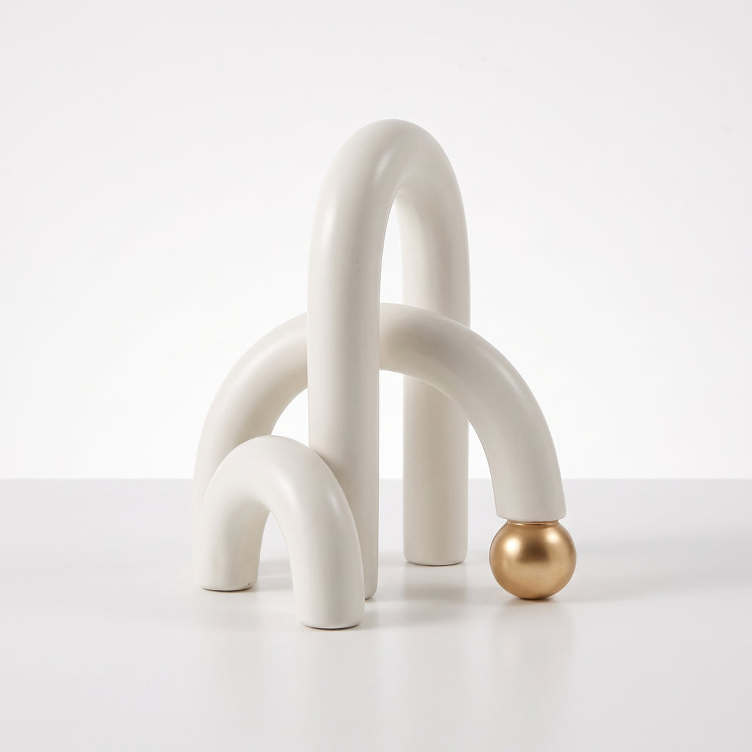 Accesorio decorativo Farid blanco con arcos curvos y detalle de esfera dorada para mesa o estante.