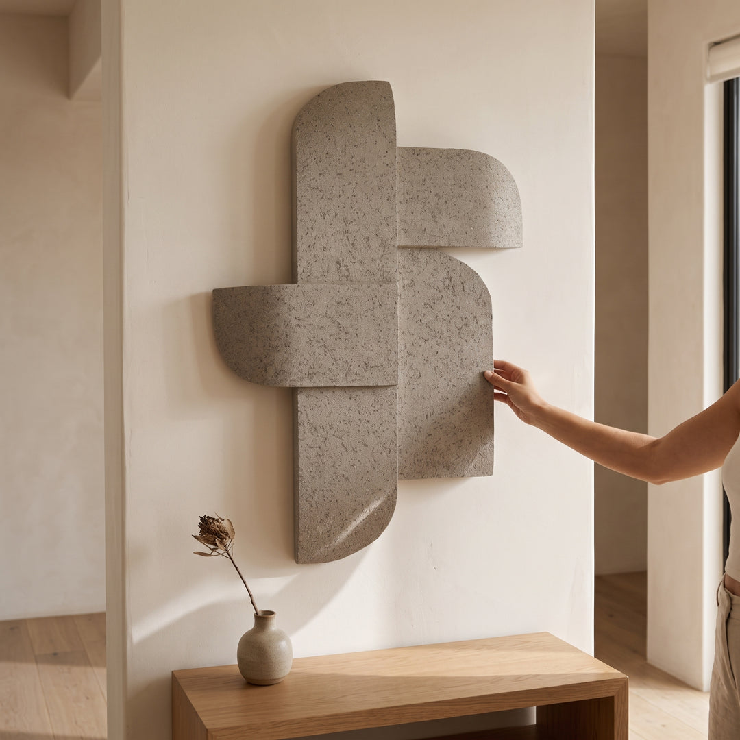 Accesorio de pared Alnir gris abstracto con relieve geométrico de piedra sobre pared y mesa de madera.
