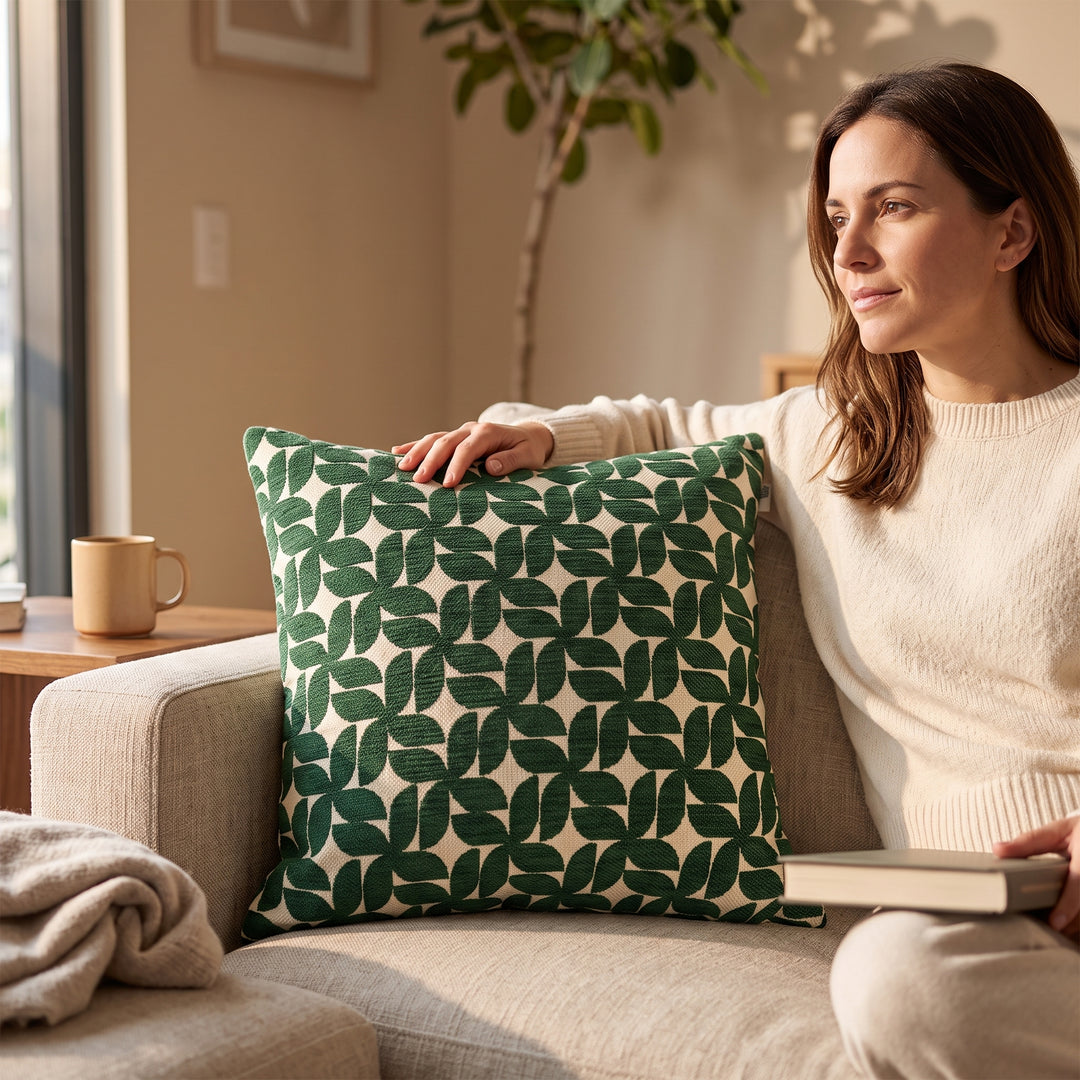 Cojín Decorativo Murcia Green 50x50 cm con Relleno en un sillón junto a una mujer.