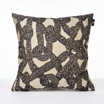 Cargar imagen en el visor de la Galería, Cojín decorativo Cleopatra 50x50 cm con diseño de nudos de cuerdas negras sobre fondo beige.