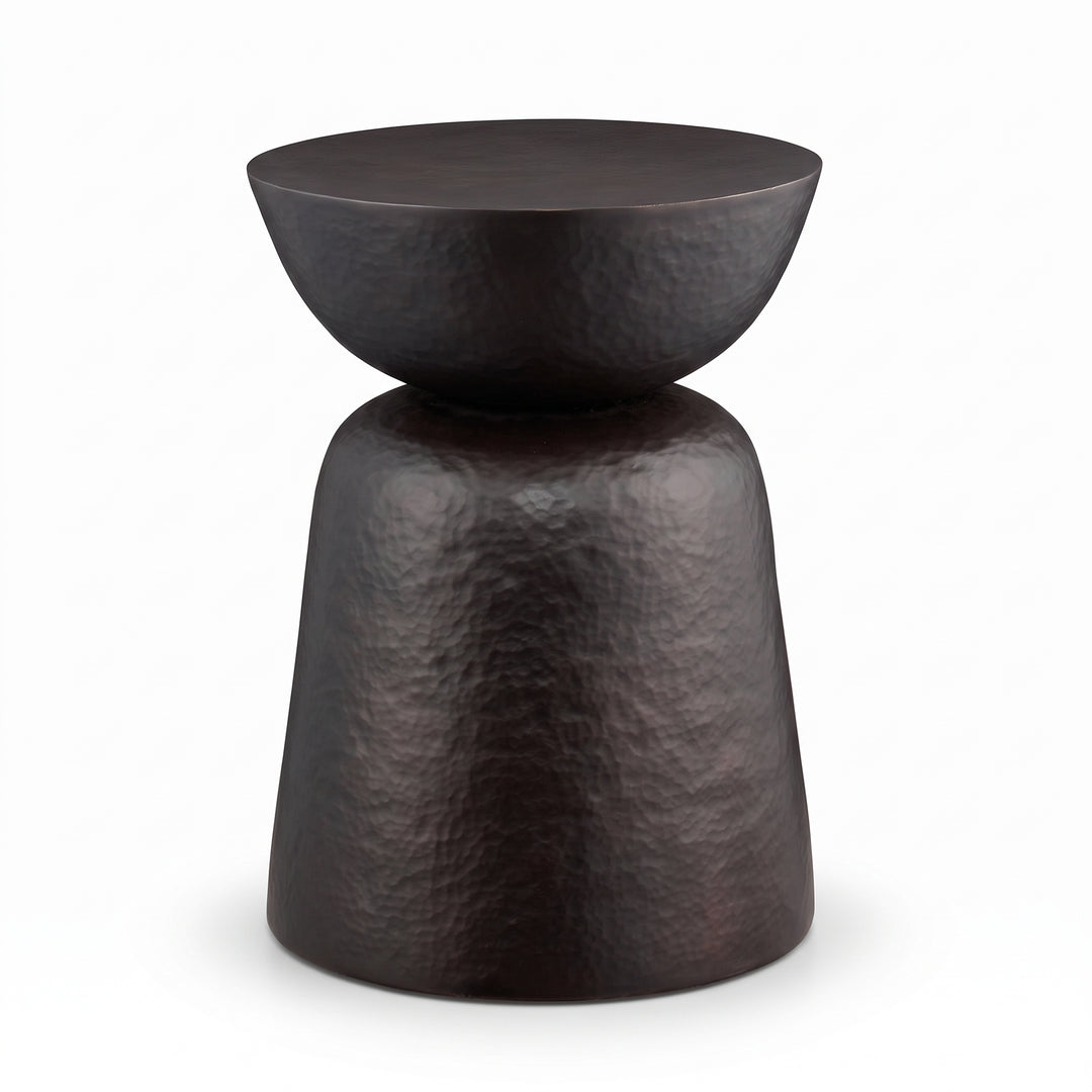 Mesa auxiliar Gladis compacta para sala o dormitorio en metal oscuro martillado con diseño escultórico.