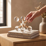 Cargar imagen en el visor de la Galería, Accesorio decorativo Veta de cristal y metal dorado sobre libros en un mueble de madera iluminado.