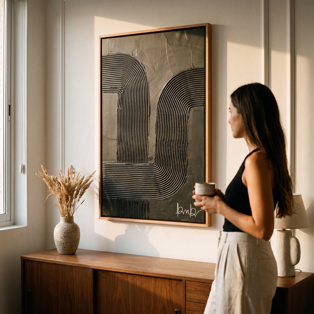 Mujer observando el Cuadro Sayil II en alto relieve con marco de madera rosa morado en una sala.