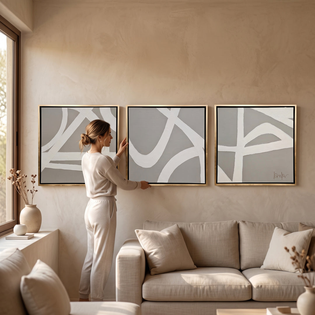 Set Arenal 3 Cuadros Decorativos 80 X 80 Marco Hoja de Oro colgado sobre un sofá en una sala moderna.