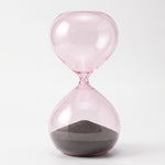 Cargar imagen en el visor de la Galería, Reloj de Arena Marea de Cristal Rosa Decorativo 27 cm con arena oscura sobre fondo blanco.