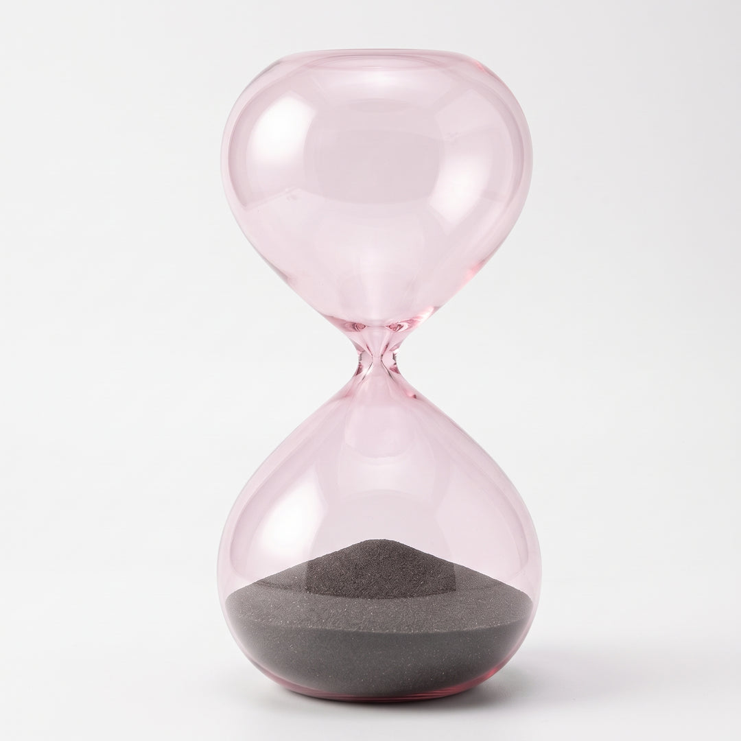 Reloj de Arena Marea de Cristal Rosa Decorativo 27 cm con arena oscura sobre fondo blanco.
