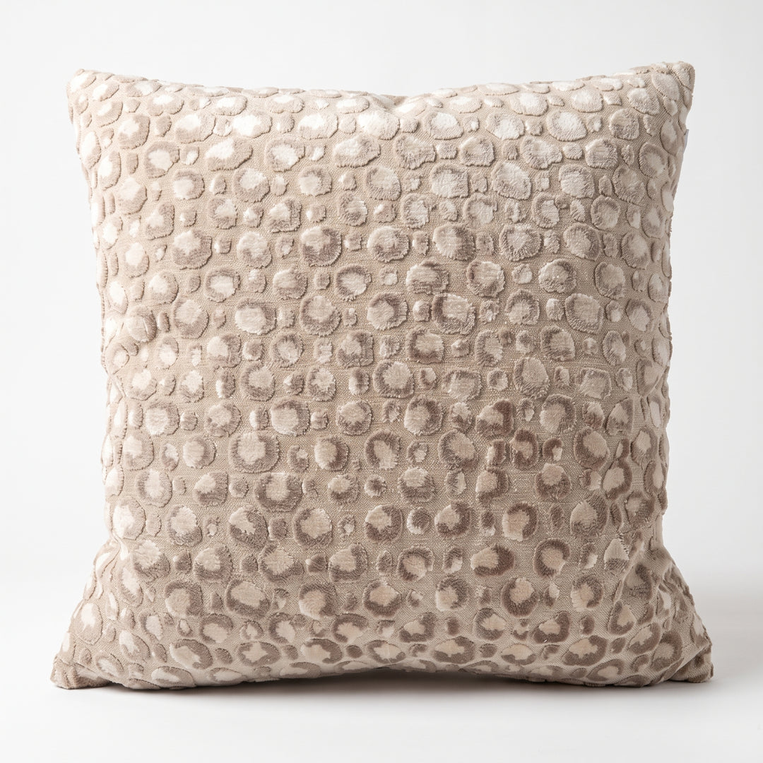 Cojín decorativo Breda Beige con textura suave de círculos en relieve sobre fondo blanco.