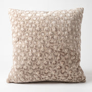 Cojín decorativo Breda Beige con textura suave de círculos en relieve sobre fondo blanco.