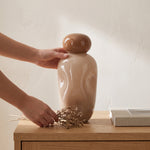Cargar imagen en el visor de la Galería, Jarrón decorativo de cerámica Versula nude y café colocado sobre una mesa de madera con flores secas.