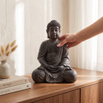 Cargar imagen en el visor de la Galería, Mano acomodando la figura decorativa Buda Halo de poliresina sobre un mueble de madera junto a libros.