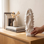 Cargar imagen en el visor de la Galería, Mano sosteniendo la escultura Virgen Huella de Esperanza en cerámica blanca sobre un mueble de madera.