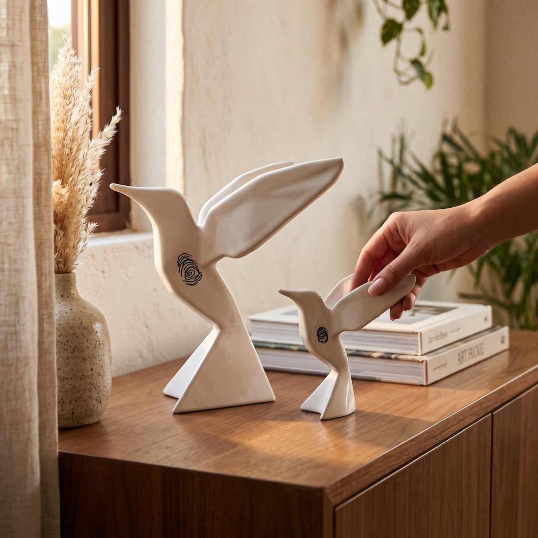 Escultura de colibrí de cerámica Huella de Magia Colección Papyro blanca sobre mueble de madera.