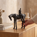 Cargar imagen en el visor de la Galería, Escultura caballo y hombre decorativa de resina sobre una credenza de madera junto a libros.