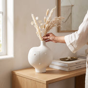 Jarrón Susan de cerámica blanca decorativo de 28 cm con flores secas sobre una mesa de madera.
