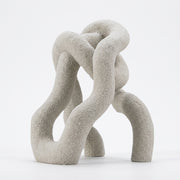 Accesorio Vania, escultura decorativa de poliresina blanca con acabado rugoso y formas entrelazadas.