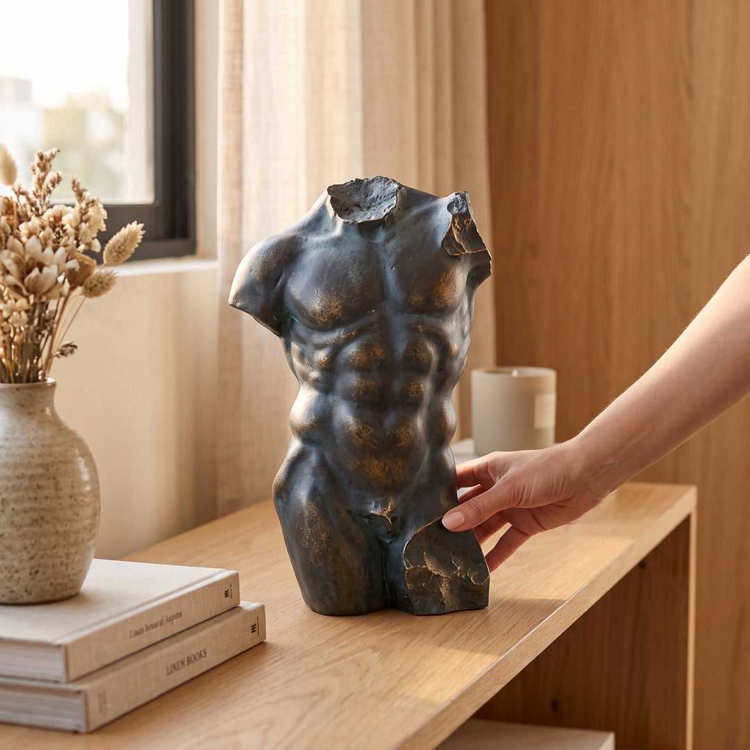 Figura Zuri, escultura decorativa de torso en poliresina sobre mueble de madera junto a un jarrón.