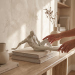 Cargar imagen en el visor de la Galería, Figura Lira decorativa de poliresina blanca de cuerpo reclinado, sobre libros decorativos en una consola.