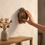 Cargar imagen en el visor de la Galería, Mano tocando el accesorio de pared decorativo Varil ocre en poliresina con forma de escarabajo en un muro.