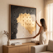 Mujer acomodando el cuadro decorativo Drif I en alto relieve con marco de madera sólida en una sala.